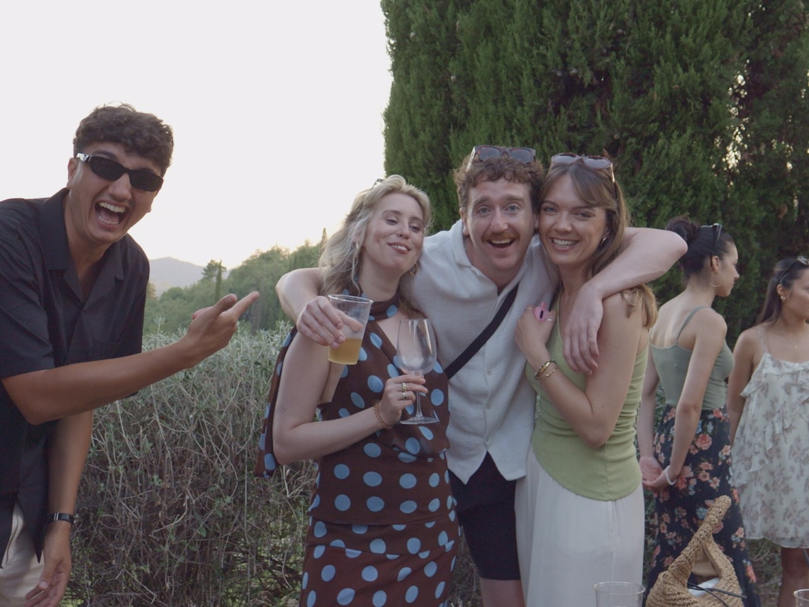 Friends laughing together with drinks in the Tuscan countryside