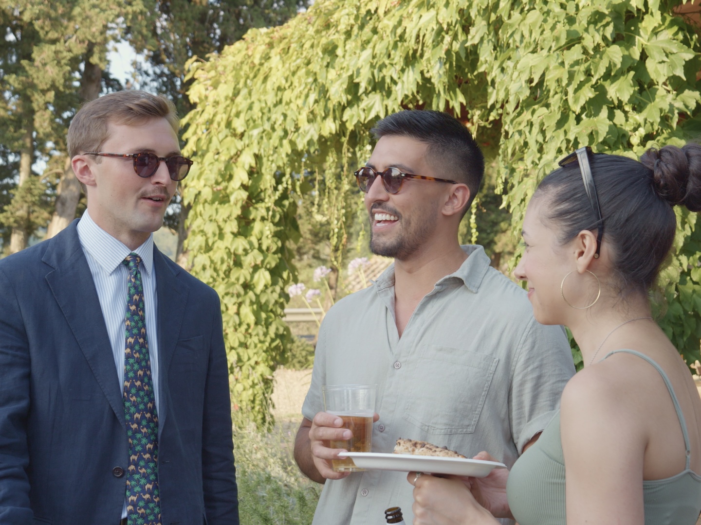 Three guests chatting with beer and pizza in the garden