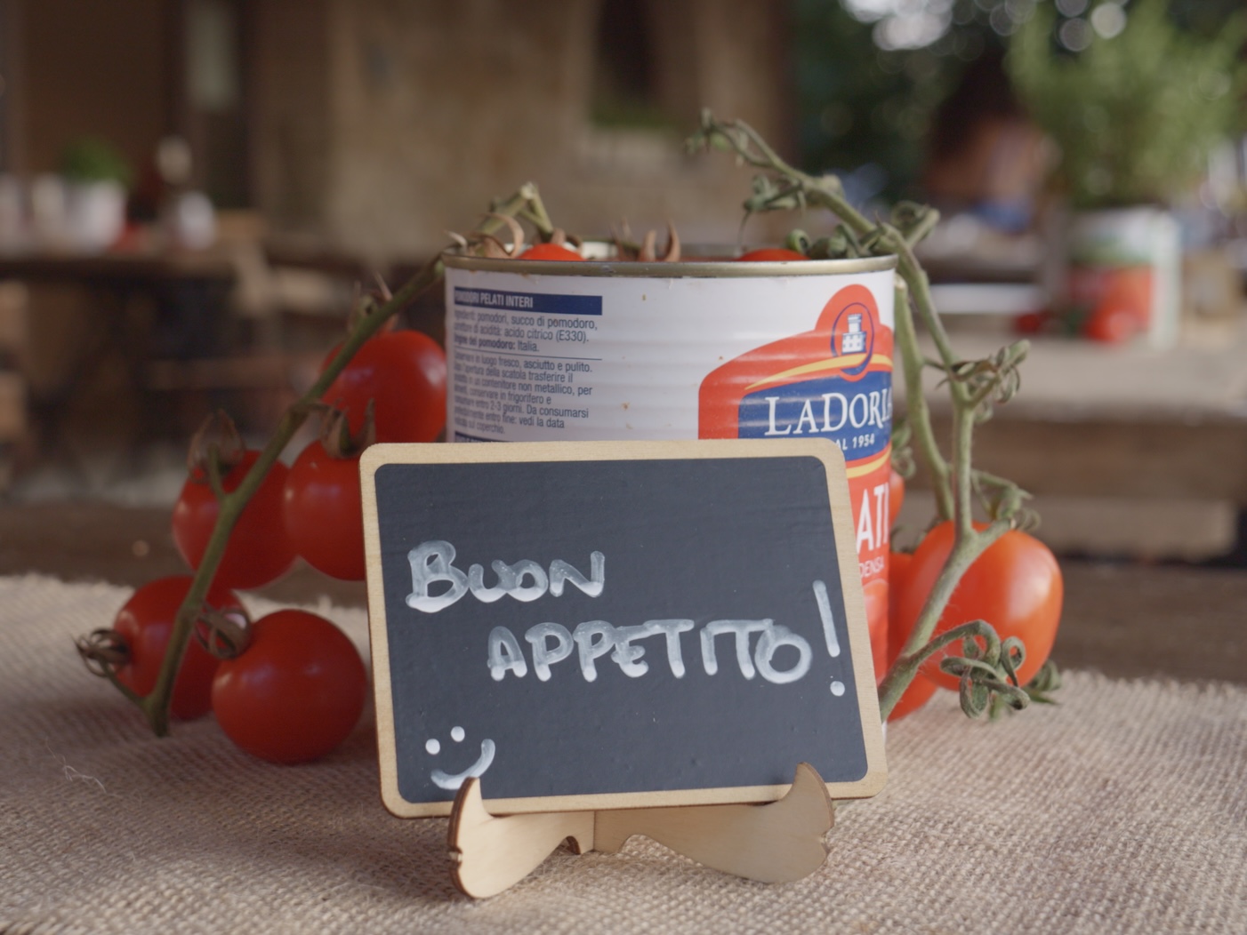 A Buon appetito chalkboard sign with fresh tomatoes and Italian peeled tomatoes