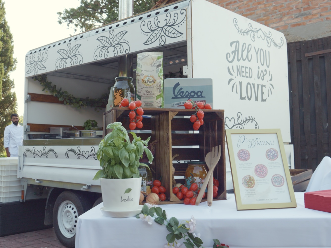 The pizza truck with fresh basil, tomatoes and the pizza menu on display