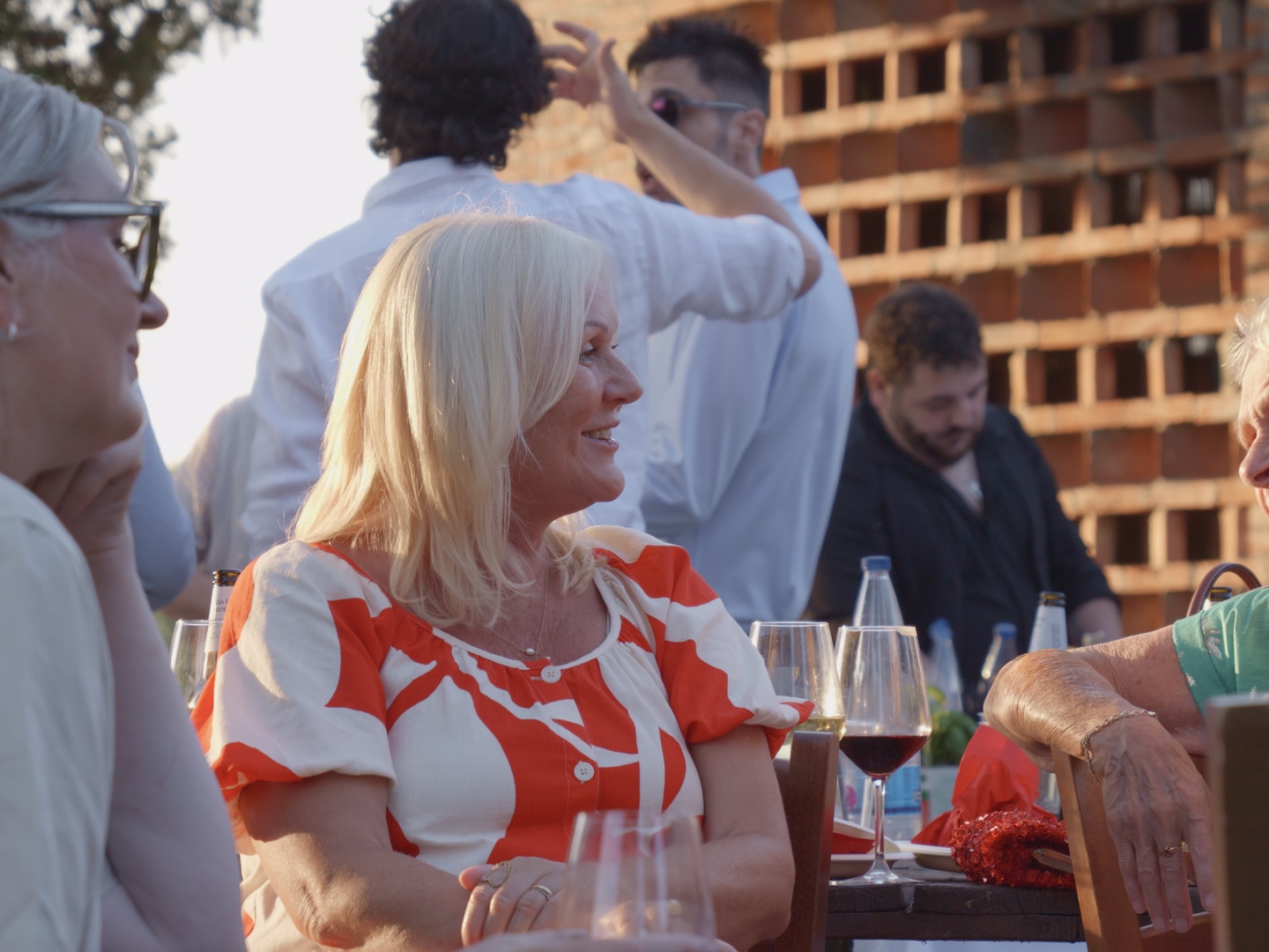 Guests laughing over wine at a long table at sunset