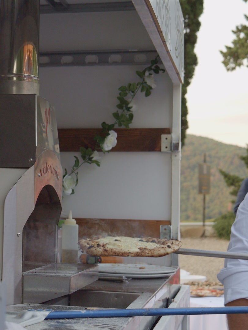 Pizza coming out of our gas oven inside the truck at sunset