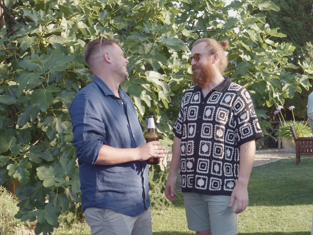 Two guests laughing with a drink in the garden of a Tuscan villa