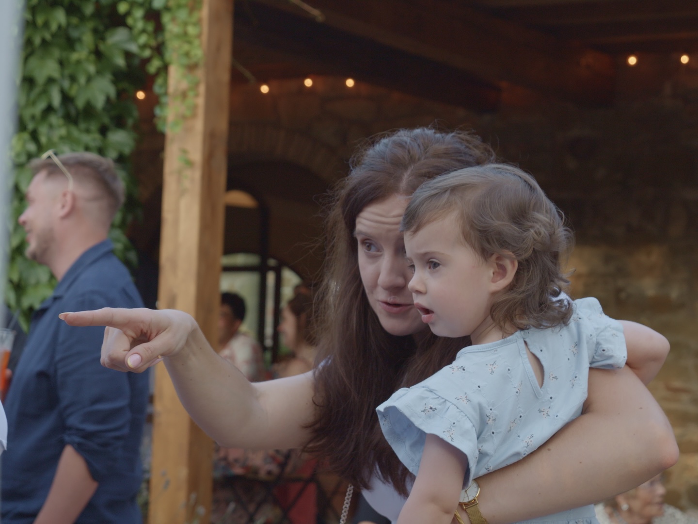 A guest holding a child and pointing towards the pizza truck