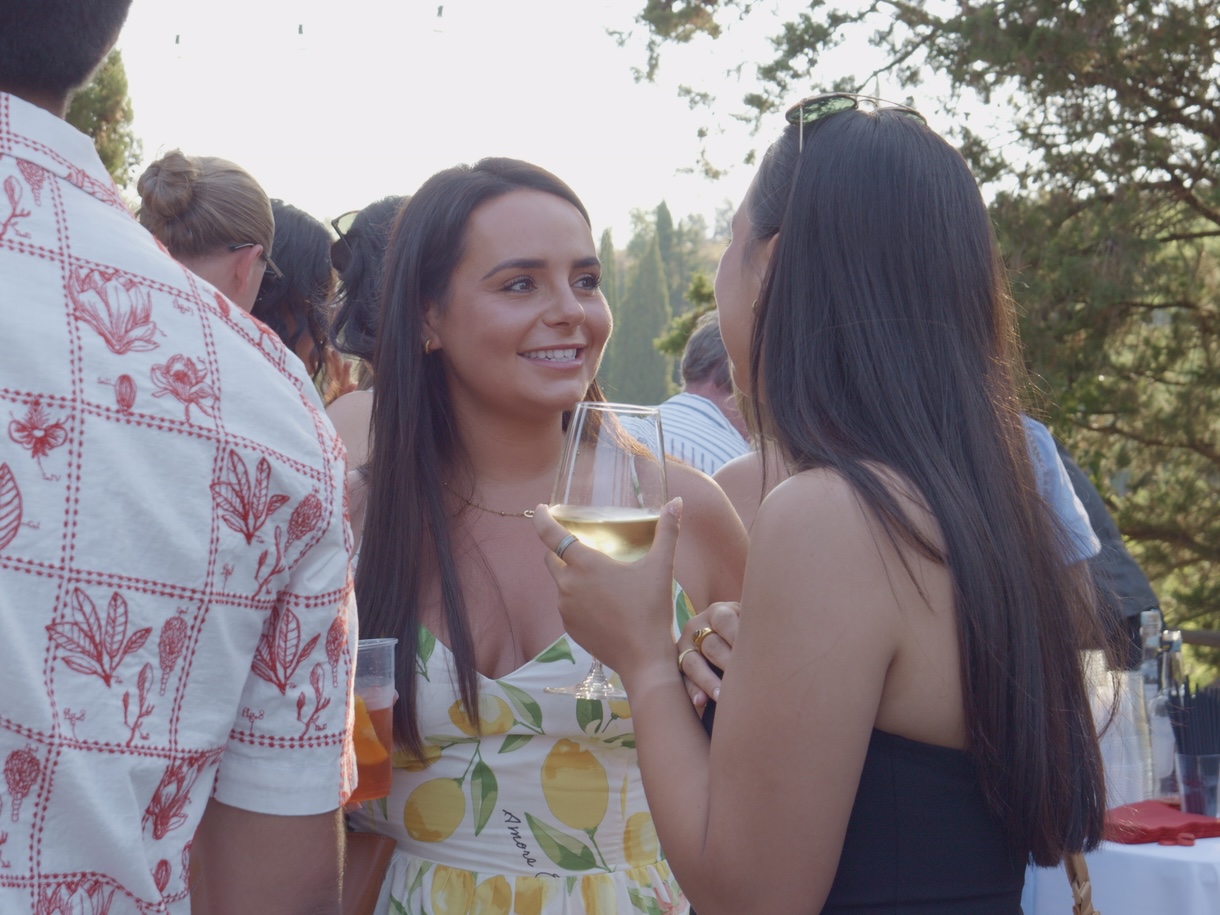 Two guests chatting with a glass of wine at golden hour